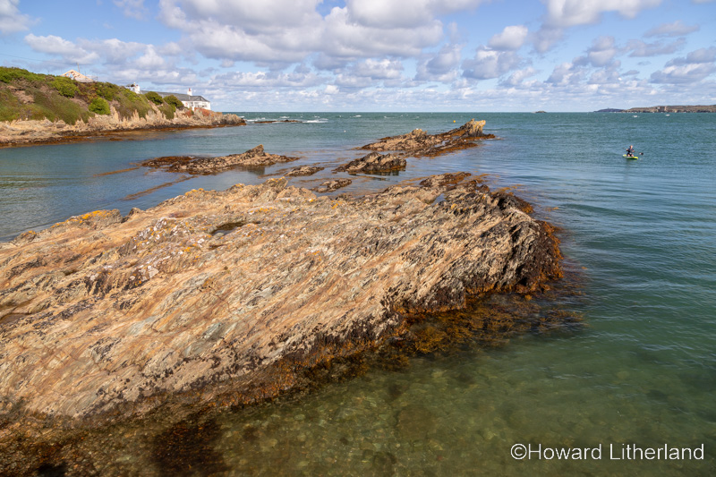 Rocks and paddleboarder at Bull Bay, Anglesey, North Wales