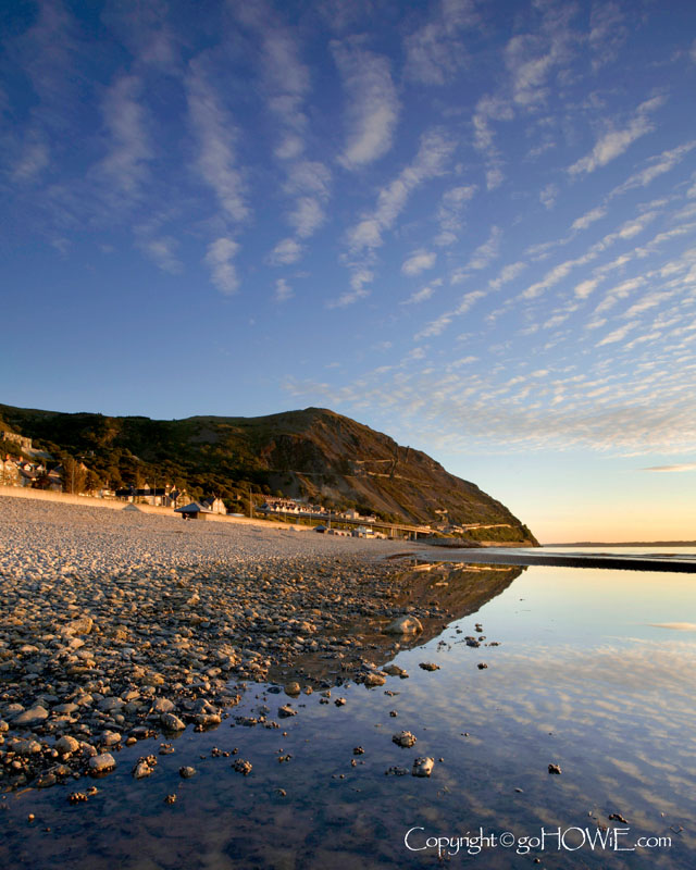 The beach at Penmaenmawr, North Wales with the reflection of the headland in a tidal pool