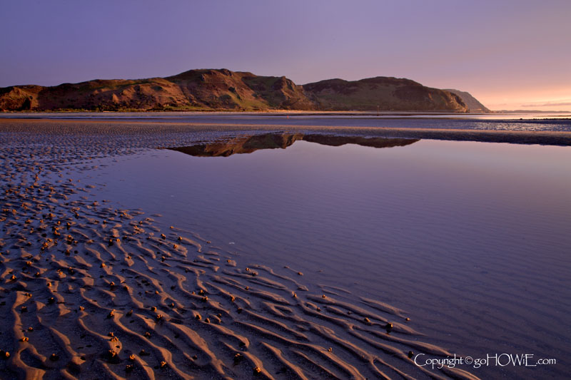 The beach at Llandudno West Shore, North Wales with the reflection of Conway mountain in a tidal pool