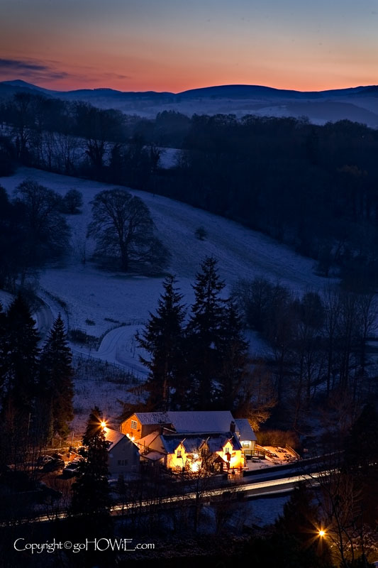 Lit buildings in snow at night, Loggerheads, North Wales