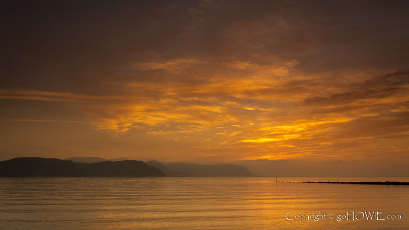 Colourful clouds reflecting in the sea just after sunset at Deganwy on the North Wales coast