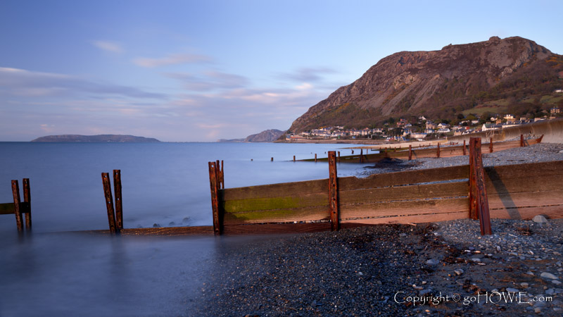 Decaying groynes on the beach at Llanfairfechan, North Wales coast, with the Great Orme in the background