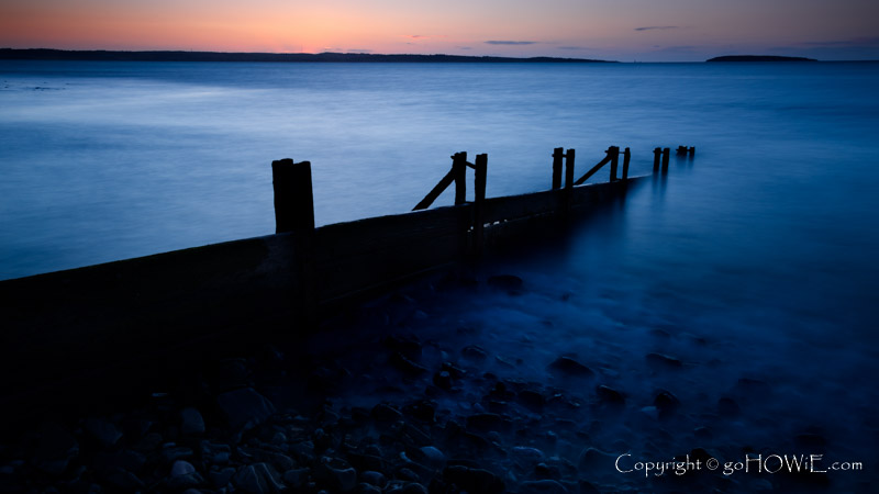 Decaying groynes on the beach at Llanfairfechan at twilight, North Wales coast