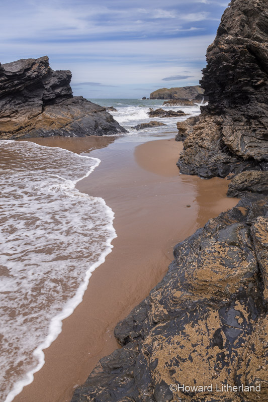 Rocks, sand and a receding wave at the beach at Llangrannog on the Ceredigion coast, Mid Wales