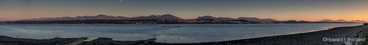 Panoramic view of the Menai Straits, Anglesey, at sunset with moon over the North Wales coast