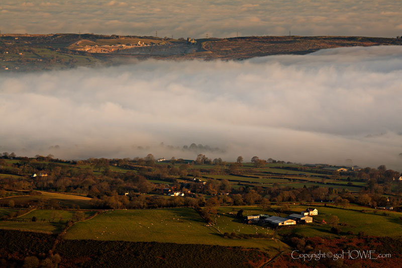 Farm in front of a layer of mist at sunrise. View is to the north from the top of Moel Famau
