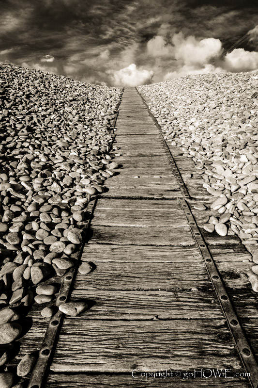 Weathered wooden boardwalk leading up a hill of shingle and pebbles at Newgale beach, Pembrokshire National Park, Wales