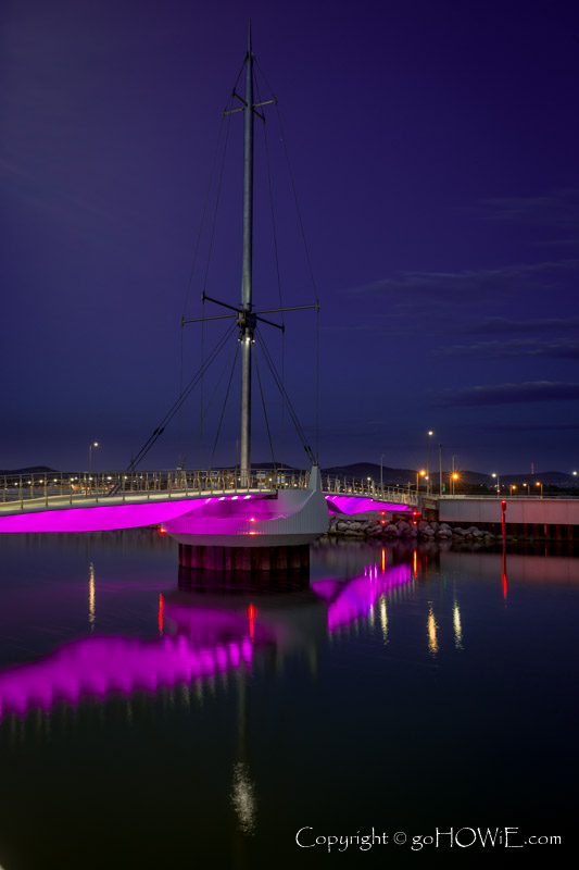 The Pont y Ddraig (Bridge of the Dragon) foot bridge, lit up at dusk at Rhyl harbour, North Wales coast